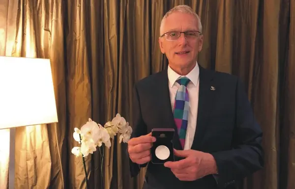 Paul Bramley in a suit and tie, holding the Callendar Medal in its open presentation case.