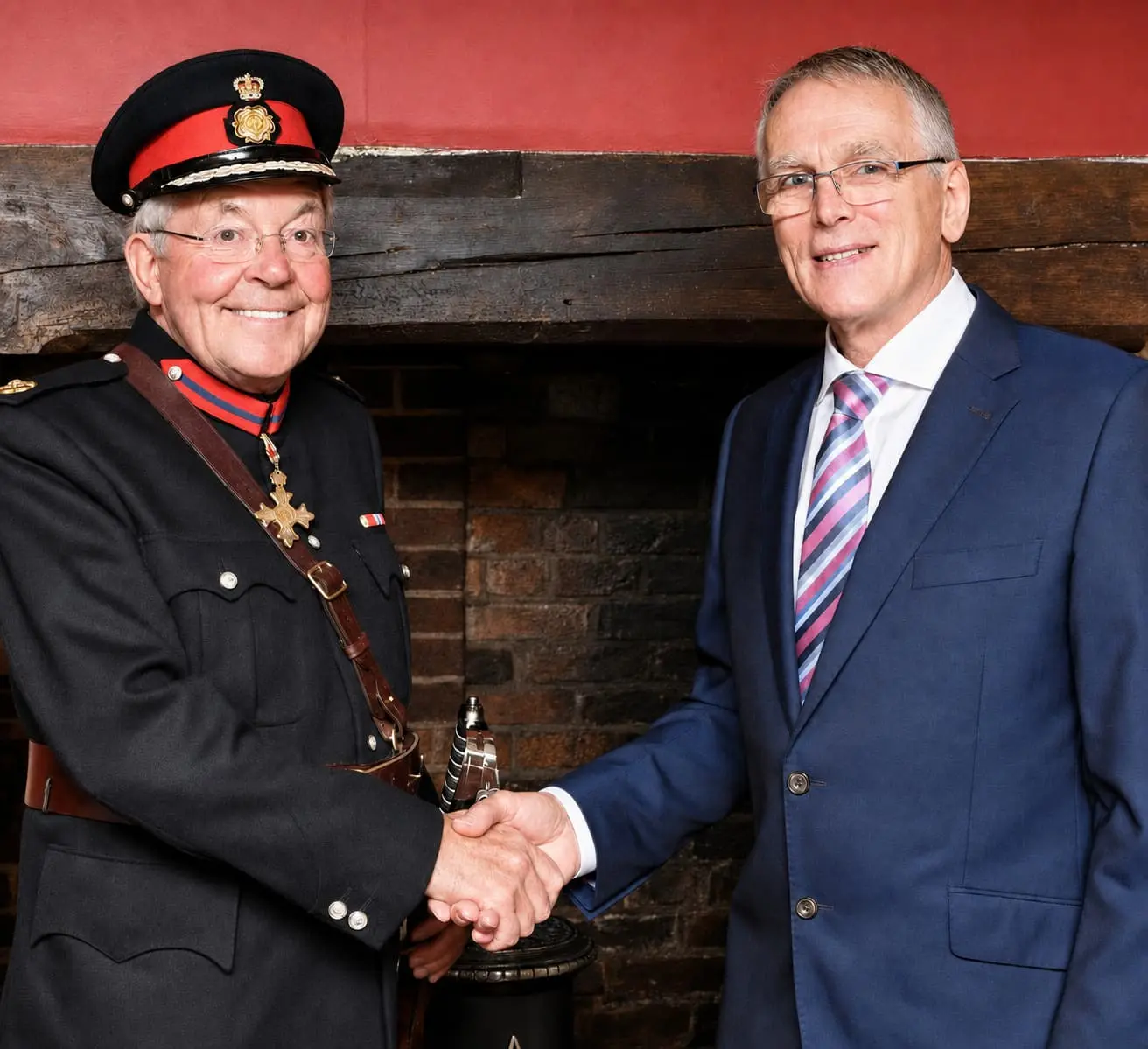 Sir Peter Ellwood CBE, Vice Lord-Lieutenant of Northamptonshire, in ceremonial uniform, shaking hands with Paul Bramley beside the Queen’s Award trophy.
